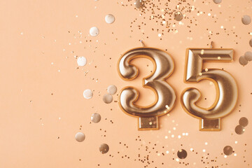 35 years celebration. Greeting banner. Gold candles in the form of number thirty five on peach...