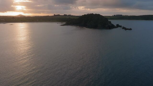 Aerial: Ocean, beach and rocky headlands in Matai Bay at sunset. Bay of Islands, Northland, New Zealand.