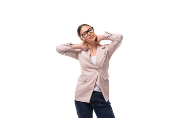 pretty smart young woman with black hair and glasses for vision is dressed in a beige jacket and jeans on a white background