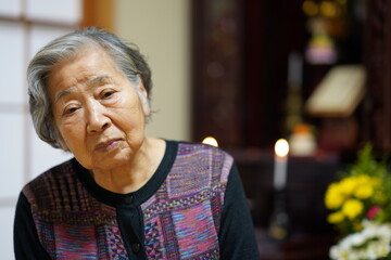 仏壇の前に座る高齢女性