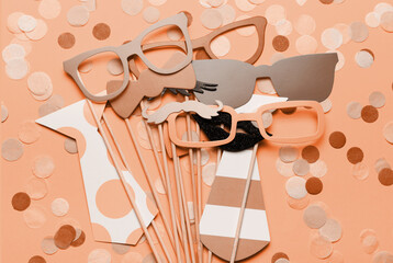 Photo booth props glasses, mustache, lips on a pink background flat lay. New trending PANTONE Peach Fuzz colour of 2024 year