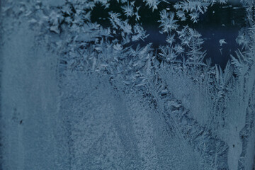 The abstract creation of window frost on window glass. Ornamental floral frost shapes on the window. Frost flowers