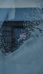 The abstract creation of window frost on window glass. Ornamental floral frost shapes on the window. Frost flowers