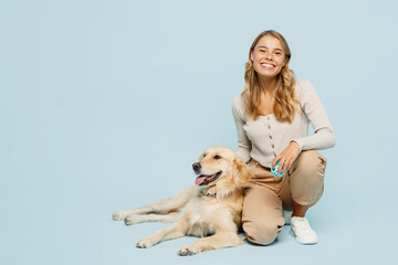 Full body smiling happy young owner woman wearing casual clothes kneeling hug cuddle embrace her best friend retriever dog isolated on plain light blue background studio. Take care about pet concept.