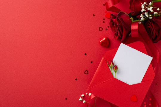 Sophisticated love expression setup. Overhead shot of elegant envelope, love declaration, heart candy, bouquet of roses, gypsophila, confetti on deluxe red background, providing space for text or ads