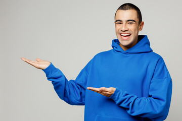 Young happy cool cheerful middle eastern man he wears blue hoody casual clothes point hands arms...