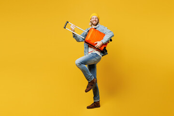 Traveler man wears denim casual clothes hold bag suitcase pov play guitar isolated on plain yellow background. Tourist travel abroad in free spare time rest getaway. Air flight trip journey concept.