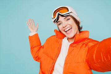 Close up skier young woman wear warm padded jacket hat ski goggles mask do selfie shot mobile cell phone travel rest going spend weekend winter season in mountains isolated on plain blue background