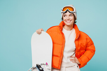 Young smiling woman wear warm padded windbreaker jacket hat ski goggles mask hold snowboard look...