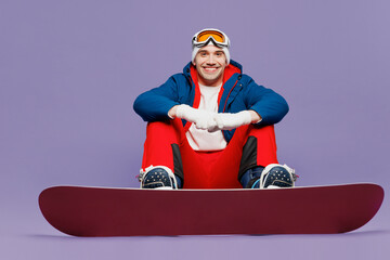 Full body smiling happy man wear blue windbreaker jacket ski goggles mask hat sitting with...