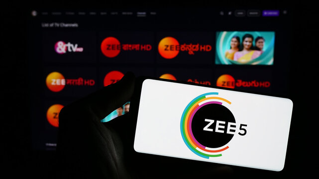 Stuttgart, Germany - 12-27-2023: Person holding smartphone with logo of Indian video streaming platform company ZEE5 in front of website. Focus on phone display.