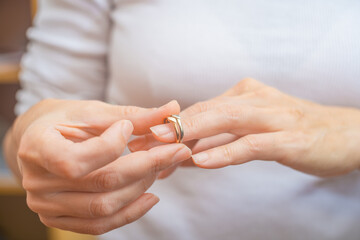 Close-up of woman's hands holding wedding ring. Focus on ring