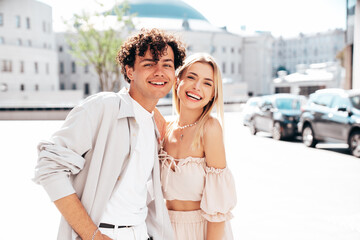 Fototapeta na wymiar Young smiling beautiful woman and her handsome boyfriend in casual summer clothes. Happy cheerful family. Female having fun. Couple posing in the street background at sunny day