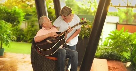 Asian Hindu happy older aged elder man male female lady wife singer artist sitting chair play guitar enjoy  rainy day fun joy music outdoor home park smiling Indian old relax couple singing song lyric - Powered by Adobe