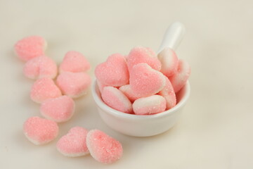 Heart-shaped pink chewy candies with sugar sprinkles on white background