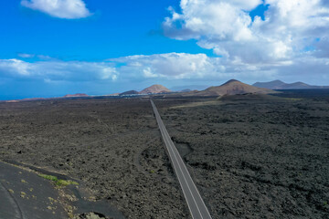 Panoramic aerial view of empty asphalt road LZ-67 in volcanic landscape of Timanfaya National Park, Lanzarote, Canary Islands, Spain, Europe