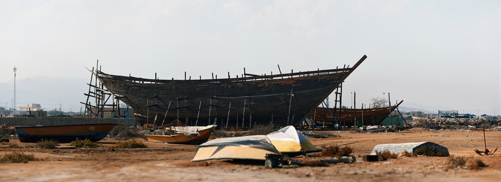 Construction of a wooden ship. Shipyard of traditional Dhow wooden boat on Iranian Qeshm Island. Tradition Lenj Fishing Boat in Qeshm Island in Southern Iran. Old wooden stealth smuggler's ship