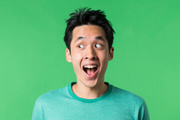 Excited Chinese man looking to left. Against green background.