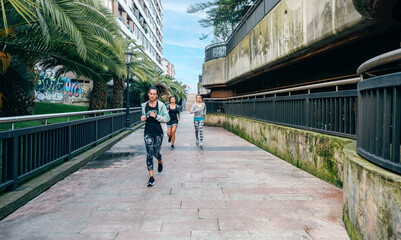 Group of young women friends runners training over a urban runway with palm trees