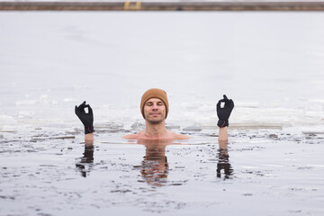 Brave man winter swimming in icy lake, showcasing Nordic lifestyle and cold exposure wellness