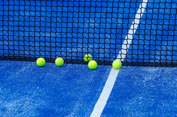 five paddle tennis balls close to the net of a paddle tennis court