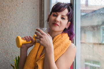 sporty young woman with dumbbells and glass of water. Workout sport concept.