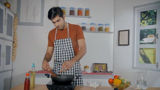 Handsome Indian guy adding red pepper powder to the food - Lal Mirch  spicy food  authentic seasoning. Home chef cooking with traditional seasoning - Indian spice  flavor enhancer  paprika  curry p...