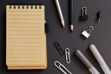 top view of school stationery with notepad over black