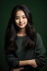 Fototapeta premium A beautiful Asian teenage girl poses for a straight-faced photo in a studio against a black backdrop.