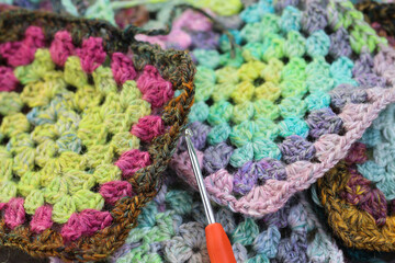 Closeup detail of crochet work grannysquare with a colourful skein of organic natural handspun and...