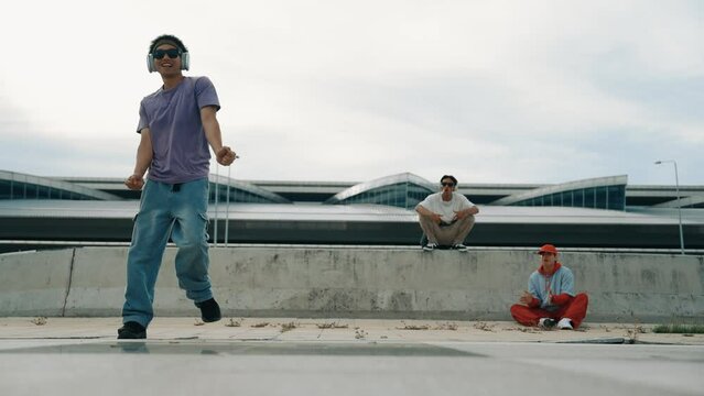 Group of asian break dancer perform street dance with multicultural friend support and moving hip hop music. Attractive handsome hipster practice b boy dance at street. Outdoor sport 2024. Sprightly.