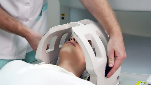 In a medical laboratory, a male radiologist performs an MRI or CT scan of a female patient undergoing a procedure. High-tech modern medical equipment.