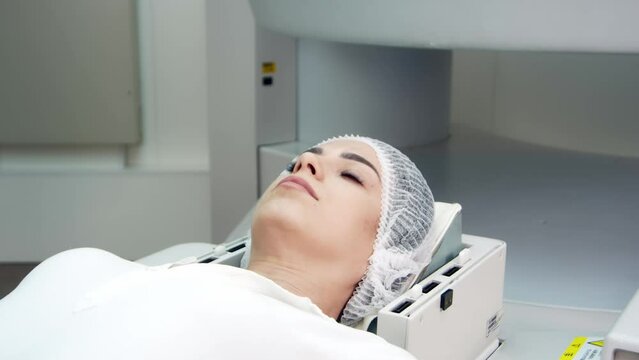 In a medical laboratory, a male radiologist performs an MRI or CT scan of a female patient undergoing a procedure. High-tech modern medical equipment.