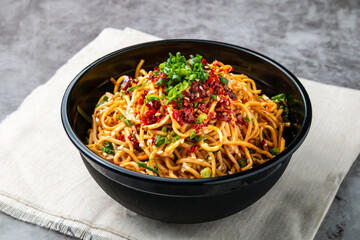 Bashu cold noodles topping with chilli paste, spring onion and sesame seeds served in bowl isolated...