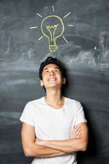 Chinese man next to chalkboard with light bulb drawn above head.