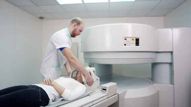 In a medical laboratory, a male radiologist performs an MRI or CT scan of a female patient undergoing a procedure. High-tech modern medical equipment.