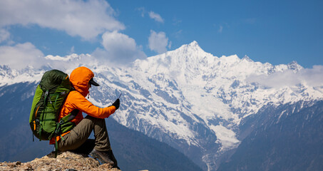 Woman backpacker taking photo of  high altitude mountains with smart phone