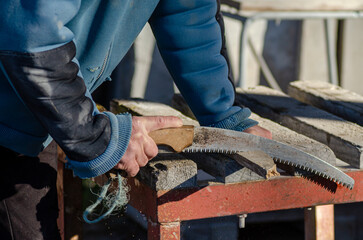 hand of a man using a saw, sawing a piece of wood