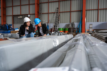 Female factory engineers working with metal sheet production line in metal manufacturing factory
