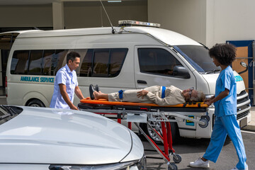 Rescue man and black nurse woman carrying unconscious elderly patient on stretcher patient in...