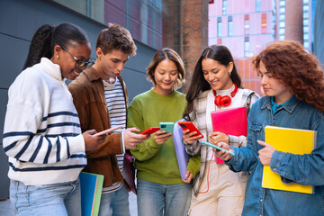 Multiethnic group of students browsing mobile phone apps outdoors.