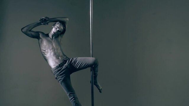 Pole dance. Sexy man dancing on pylon. Sexy slim and muscular male body. Flexible man gymnastic dancer man performing. Strong guy on pole dance. Shirtless gymnast exercising on pylon. Bare male torso.