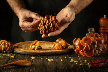 A large bunch of fresh wild mushrooms in the hands of a chef before sorting and cooking. The...