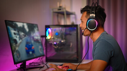 Side view of joyful male gamer in headphone playing video game on computer at home