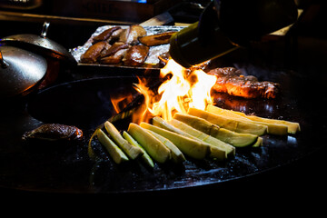 Cooking sausages and grilled vegetables over a campfire. Recreation and summer camping in the...