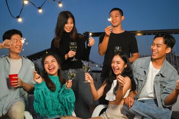 Group of young adult friends laughing and having fun at rooftop party. Friendship lifestyle concept