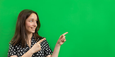 Woman pointing at a green cardboard empty background - copy space for text.