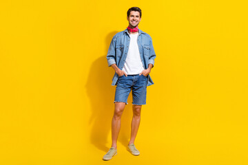 Fototapeta na wymiar Full size photo of confident positive guy wear jeans jacket shorts standing arms in pockets isolated on bright yellow color background
