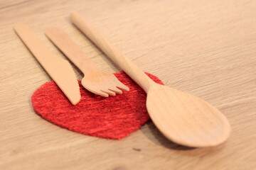 wooden knife wooden fork and wooden spoon on heart shape
