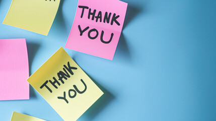 The sentence Thank you written by hand on a yellow post it and put on the white table